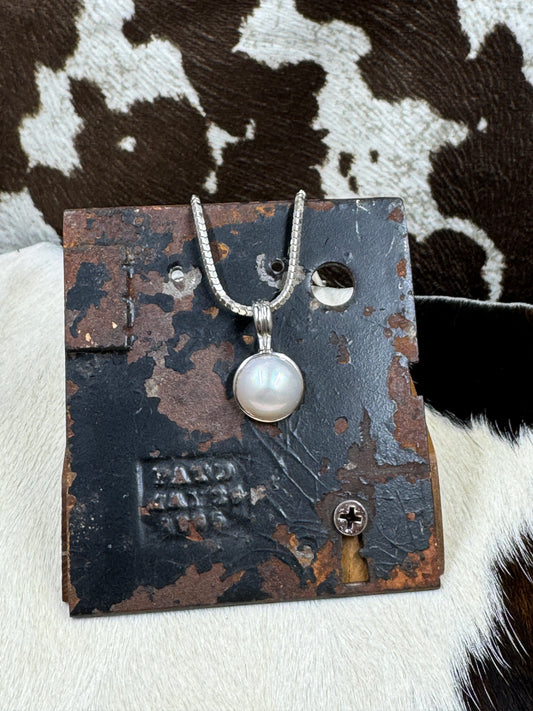 Faux Pearl and Sterling Silver Necklace Enhancer on metal background with cowhide background