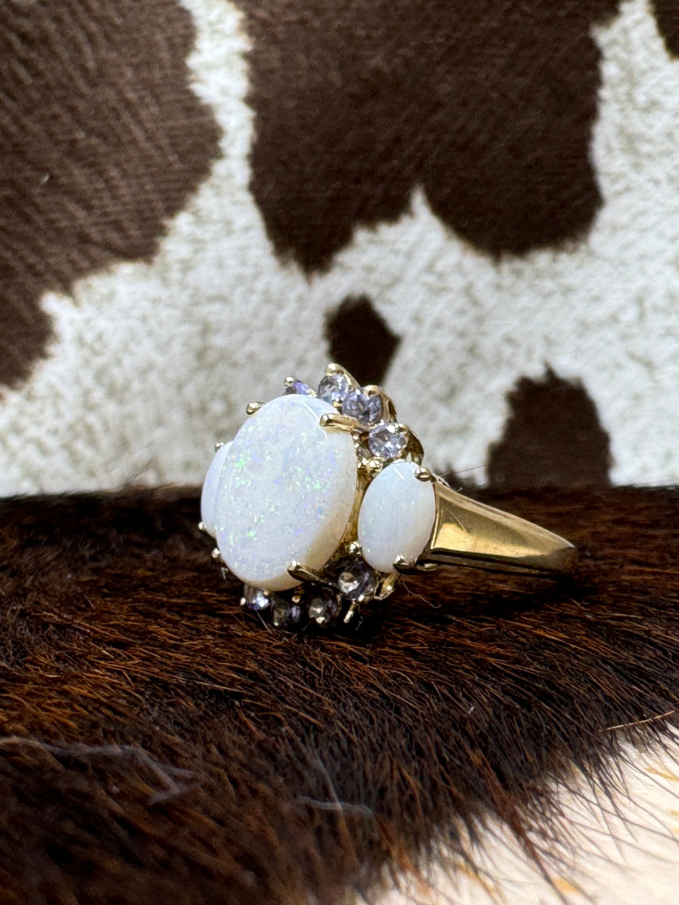 Tanzanite and Opal 10K Gold Ring on cowhide with cowhide background